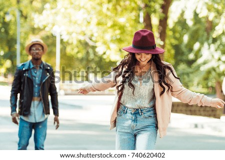 Boyfriend looking at his girlfriend skateboarding in a park