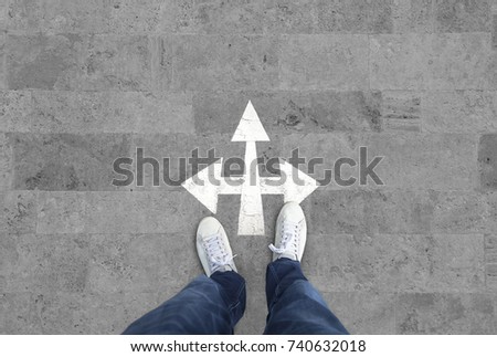 Man at white arrow intersection sign Royalty-Free Stock Photo #740632018