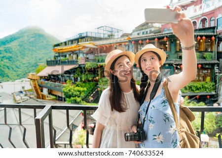 two beautiful girls taking selfie photo of famous landmarks Amei tea house of Jiufen Taiwan. Travel holiday vacation concept.
