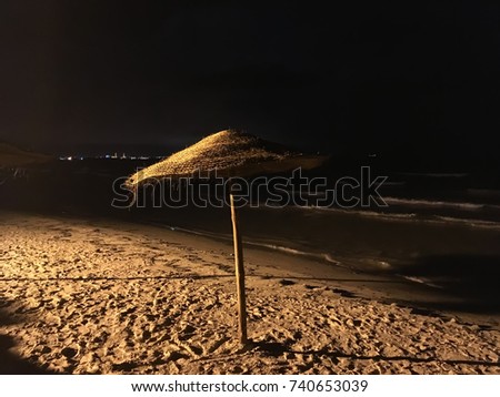 Beach straw umbrella on the sea shore by night