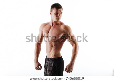 Picture of strong handsome young sportsman standing isolated over white background and posing. Looking aside.