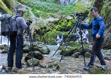 Professional photographers with cameras on tripod shooting in a river
