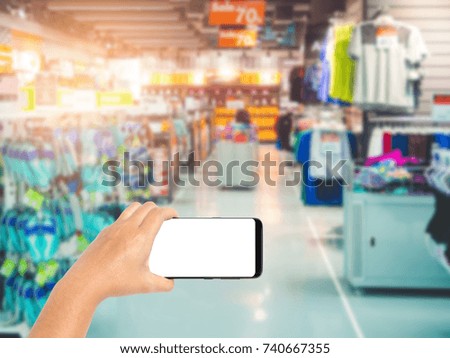 Hand holding smartphone on sport department store background blurred, Shopping centre mall 