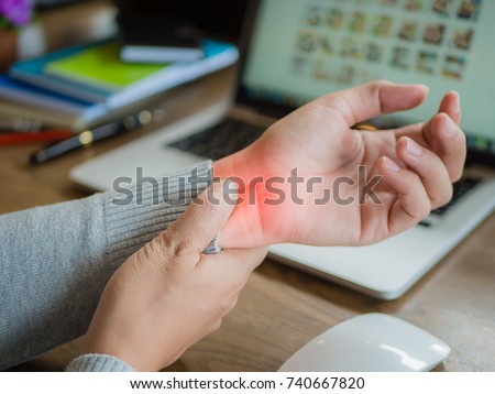 Closeup woman holding her wrist pain from using computer long time. Office syndrome concept. Royalty-Free Stock Photo #740667820