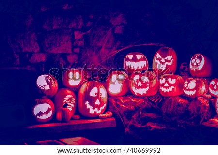 Glowing jacko lanterns carved from real pumpkins at night.