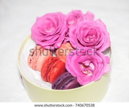 A gift box with colorful macarons and pink rose flowers