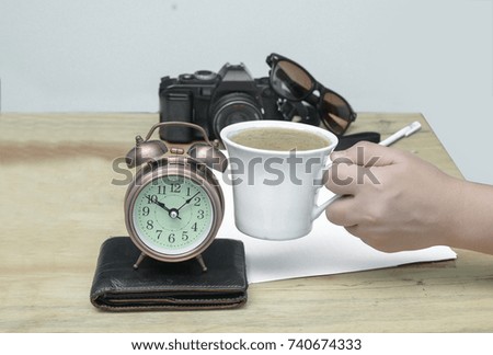 Hands holding hot coffee with clock, coffee break concept.