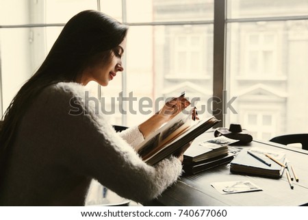 Dreamy lady sits with old photo-albums in the cafe