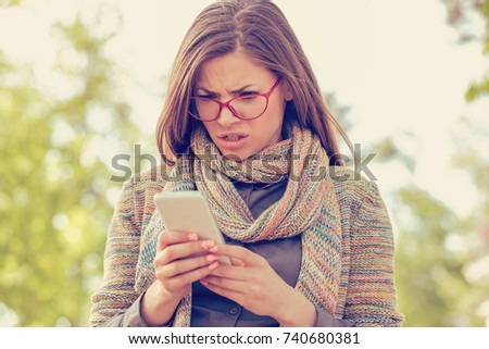 Woman looking angry at the phone  Royalty-Free Stock Photo #740680381