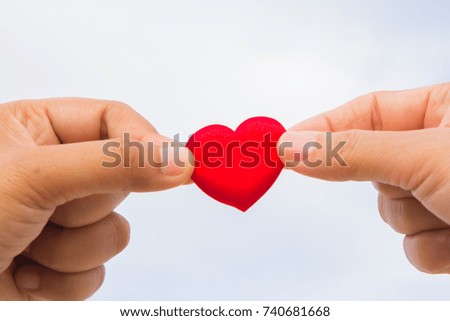 Two hand with red heart, sky background.
