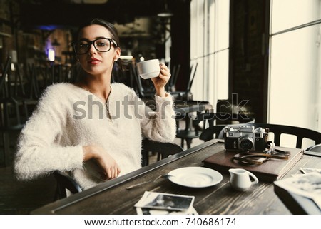 Pretty young woman sits with cup of coffee in the cafe