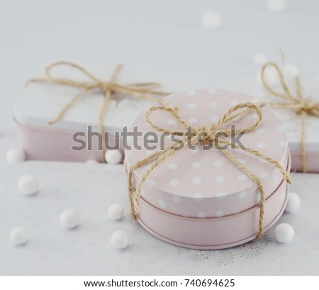 Cute gift boxes in pastel colors on the gray background. White and pink presents with bows and ribbons.