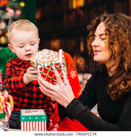 Mom has fun with her son sitting in the room dressed for Christmas and New Year