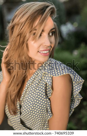 Outdoors portrait of beautiful young woman in casual clothes posing in autumn garden.