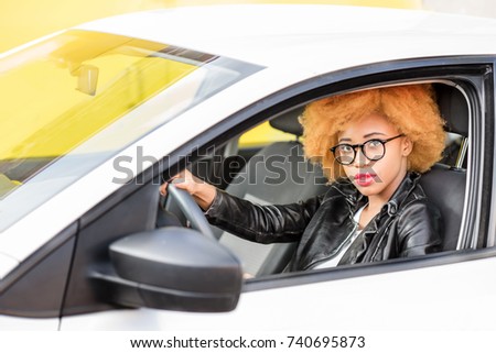 Portrait of a beautiful african woman in leather jacket sitting in the car on the yellow background