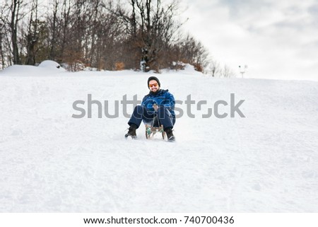 Bearded man sleighing down hill on the snow