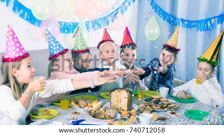 Smiling children enjoying friend`s birthday during festive dinner
