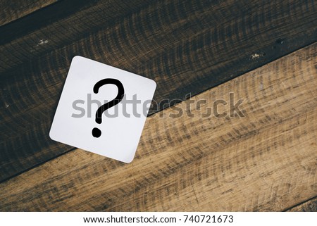 question mark on white note on a wooden background
