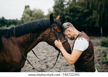 Handsome man with big horse in the forest 