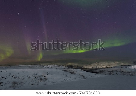 Snow covered the hills and in the sky stars, clouds and northern lights.Horizontal.