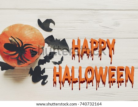 happy halloween text flat lay. jack lantern pumpkin with witch ghost bats and spider black decorations on white wooden background top view, space for text. seasonal greetings. 