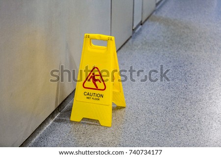 Yellow plastic warning wet floor sign standing on the ground