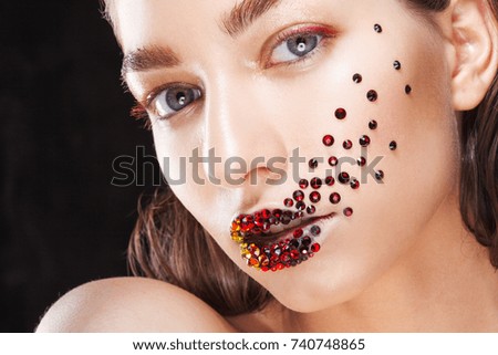 Young beautiful girl with blue eyes. Bright makeup, red lipstick. Art, rhinestones on the lips and face