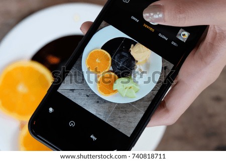 People use cell phone to take a photo of chocolate lava cake with orange slices, green apple slices, vanilla ice-cream and wiped cream