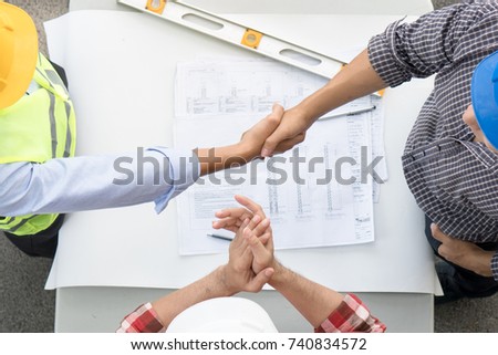 Successful deal, Engineer / contractor shaking hands with client in construction site after confirm blueprint for renovate building. Royalty-Free Stock Photo #740834572