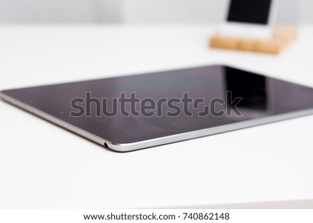 Tablet and smart phone on a white office desk both with blank screen