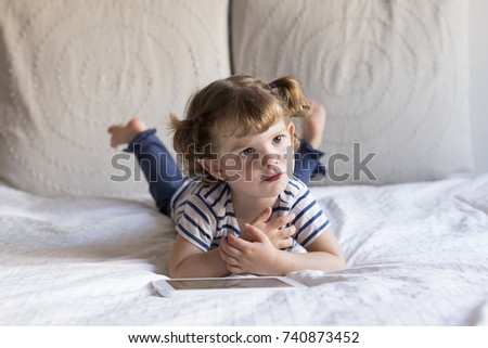 beautiful little girl using tablet on bed. Home, indoors. LIfestyle
