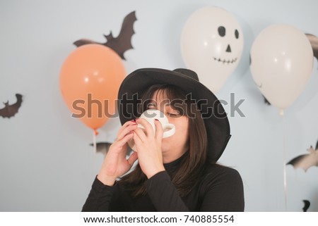 Girl in black dress is holding white mug in hands. Mockup for Halloween gifts design.