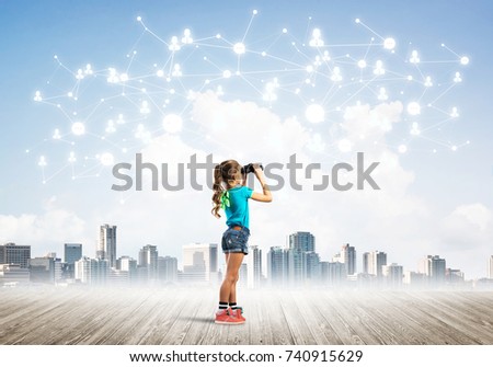 Cute kid girl standing on wooden floor and looking in binoculars