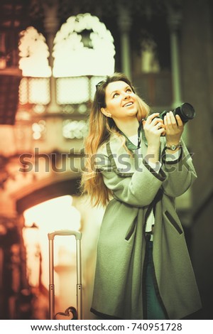 Blond  smiling young girl holding camera in hands and photographing in the city