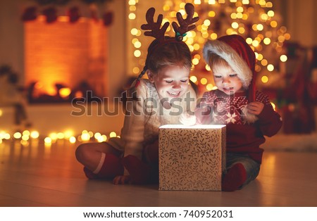 Merry Christmas!happy children with magic gift at home near  Christmas tree and fireplace