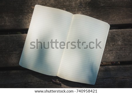 Blank empty moleskine notepad see from top on wooden table in a park