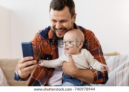 family, parenthood and people concept - happy father with little baby boy taking selfie at home