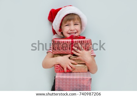 Happy child in Santa red hat holding Christmas presents. Christmas time.
