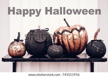 Black and rose cold colored pumpkins against white wall. Happy Halloween text. Copy space