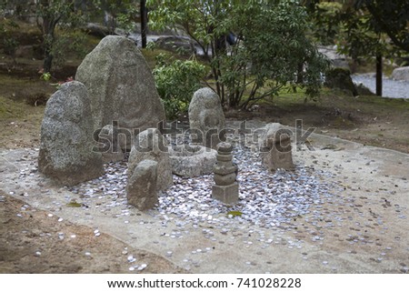 Stone Idols with lot of coins on earth. Golden Pavilion or Rokuon-ji, or Kinkaku-ji, Kyoto, Japan.