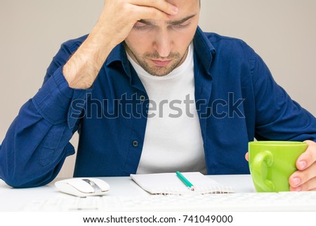 man, upset, holding his head on hands, looking at his notes, office work