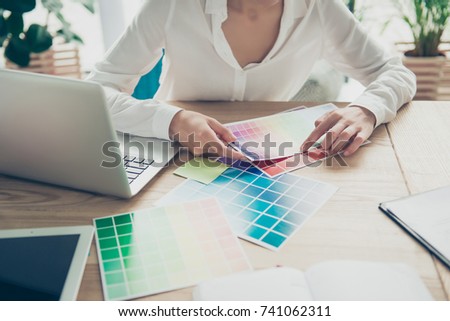 Creative occupation, making decision. Close up cropped of female architect, choosing the colors for new project, looking at the pantone, in formal wear, sitting at the wooden table