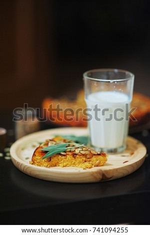 a piece of fragrant pumpkin pie and a glass of milk on black rustic table, top view closeup