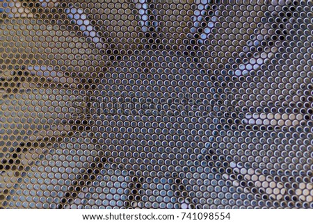 Black metal mesh with fine perforation, under it a fan for cooling the processor. Daytime side lighting.