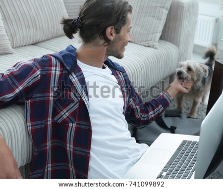 stylish young man stroking his pet and working on laptop