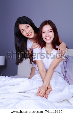 best friend woman sitting and smilling on bed in the bedroom