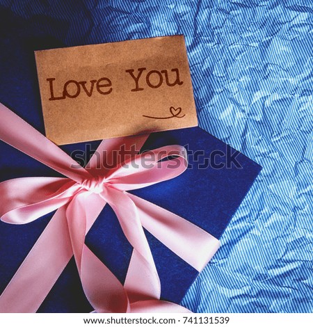 The Dark blue gift box with  ribbon decoration and Love You text card on polka blue paper , Happy Father's Day or celebration gift concept , top view and overhead shot , right copy space background