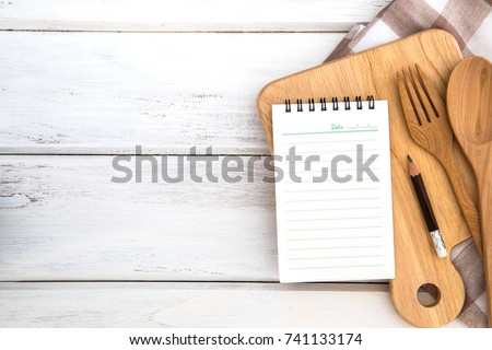  Notepad on chopping board with wooden fork and spoon  on white table , recipes food or diet plan for healthy habits shot note background concept Royalty-Free Stock Photo #741133174