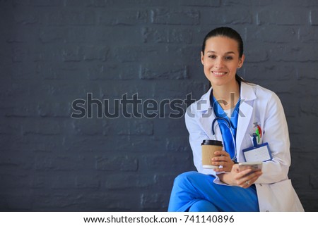 Young woman doctor sitting with your phone. Woman doctors.