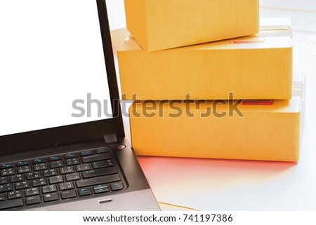 Online shopping / ecommerce and delivery service and logistics technology business industrial concept. Heap of stacked corrugated cardboard package boxes on laptop. 
